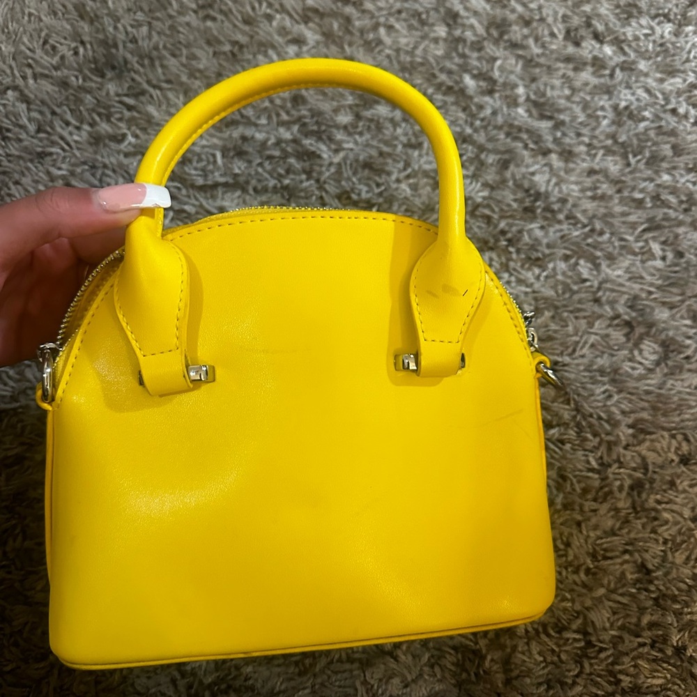 Yellow shoulder bag with silver hardware and zipper closure.